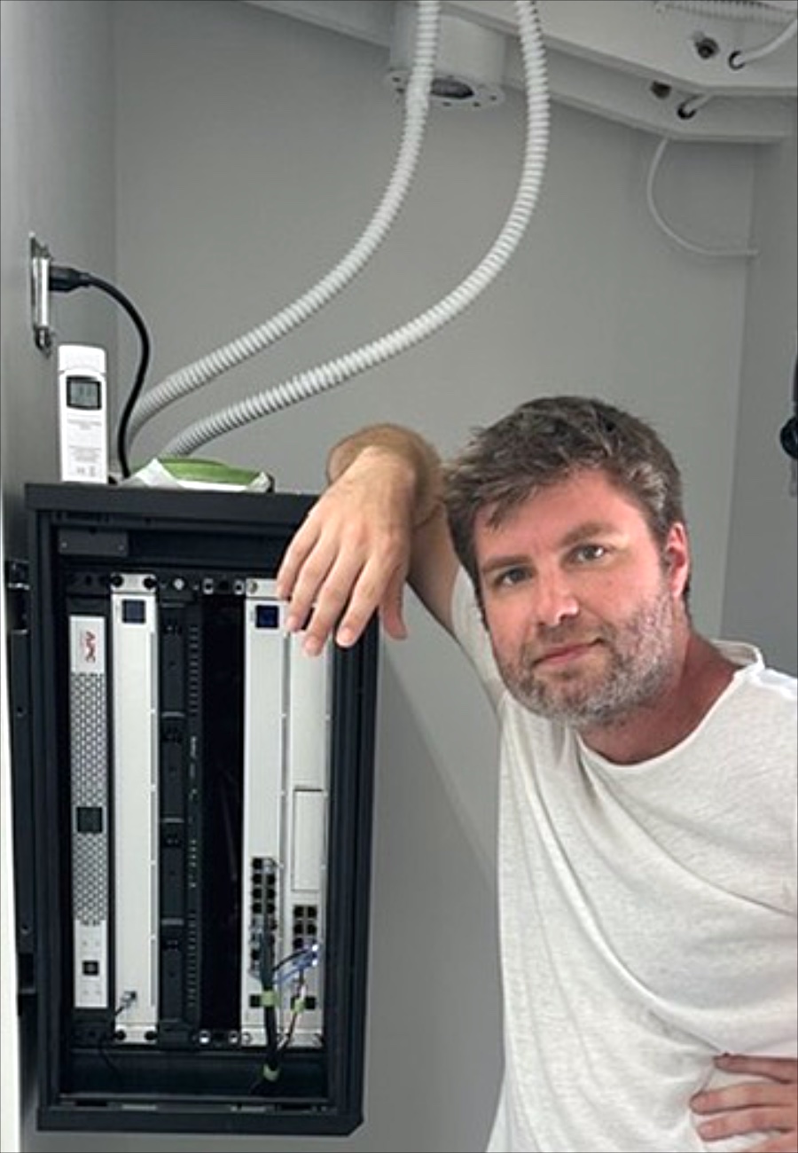 Andrei Gorbis beside a network rack installation