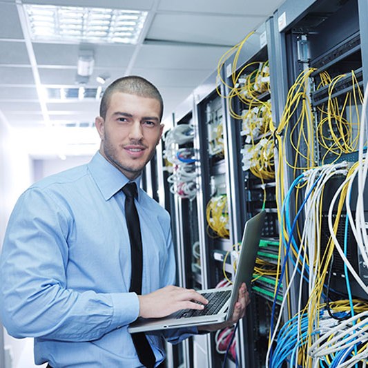 Businessman with laptop in network server room